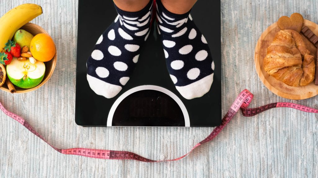 close up of feet on a weight scale looking how much is her weight and if she has losed weight